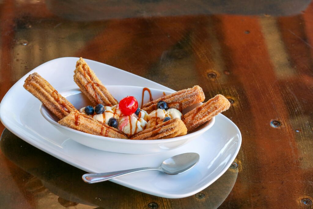 A tempting plate of churros served with ice cream, blueberries, and a cherry.